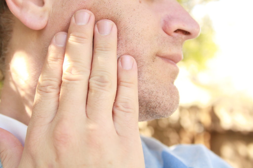 Man with TMJ holding his jaw